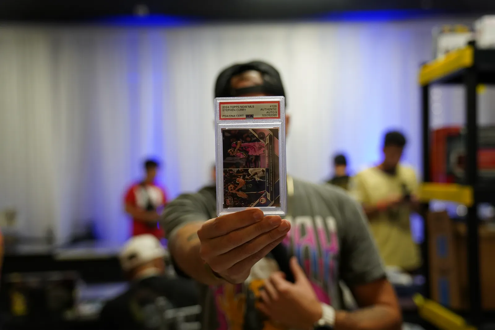 A collector holds up a graded PSA-authenticated Stephen Curry card for the camera