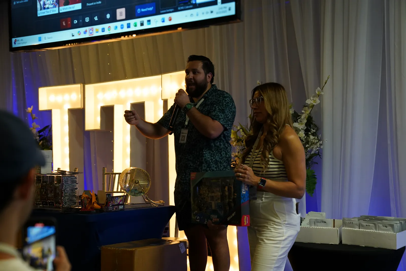 Hosts announce raffle winners on stage with a prize box and raffle drum