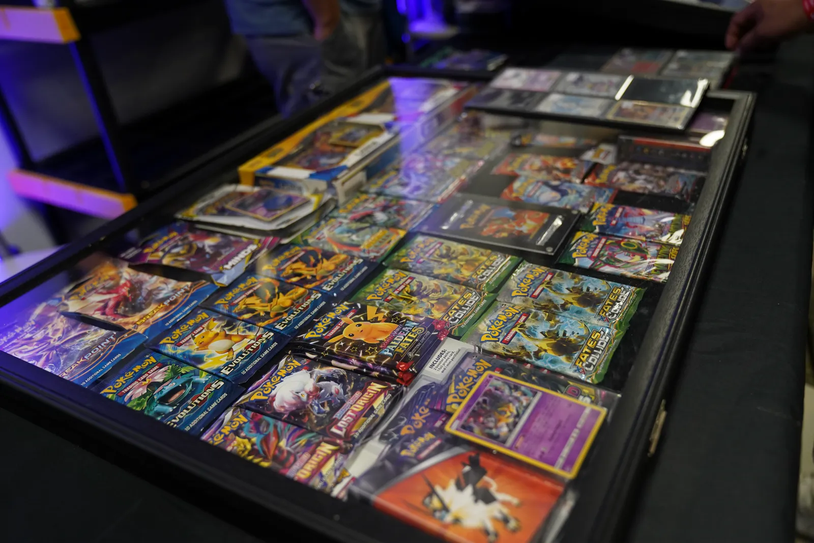 A display case of sealed Pokémon booster packs and collector tins