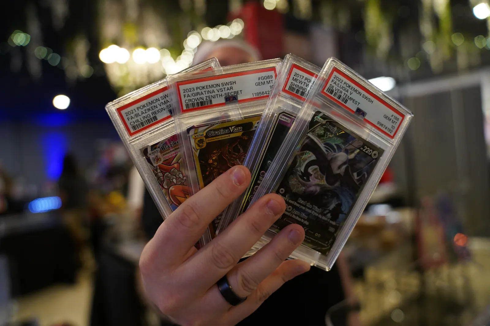 A collector fans out four graded Pokémon cards for the camera