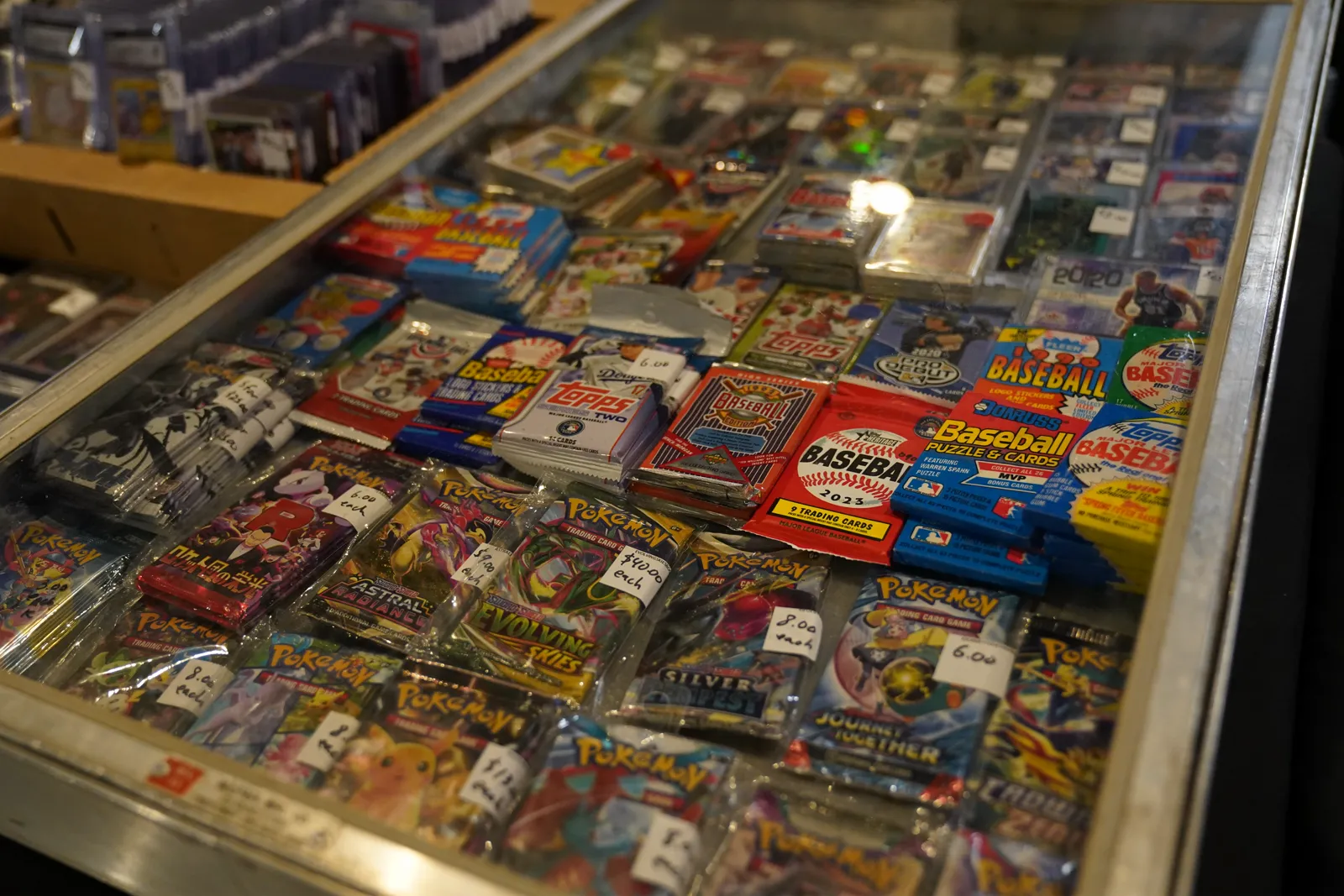 A display case filled with sealed baseball and Pokémon trading card packs