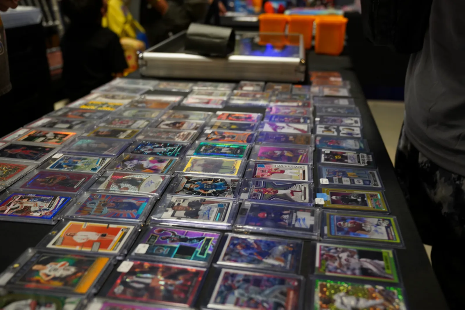 Rows of graded sports and Pokémon cards laid out on a vendor's display table